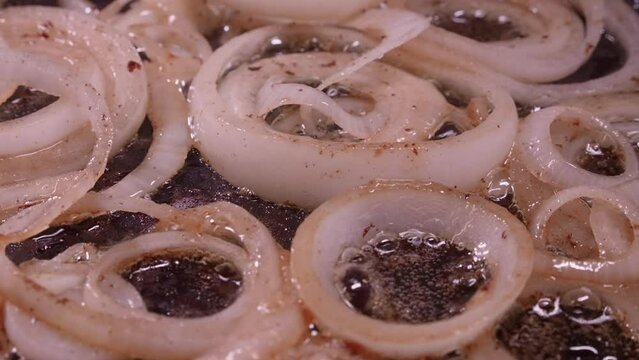Full frame closeup: Onion rings fry, sizzle in hot oil in frying pan