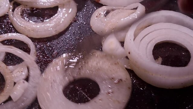 Fresh raw onion rings sputter in hot oil skillet on stovetop