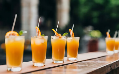 Cocktail glasses on outdoor bar tabr with orange drinks at shallow depth of field