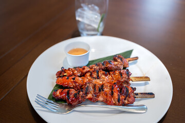 Grilled pork ribs with sauce on white plate and wooden table, Philippines

