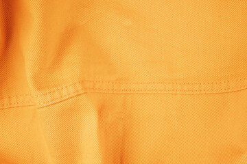 Yellow denim folds close-up, seams on a yellow denim jacket close-up.