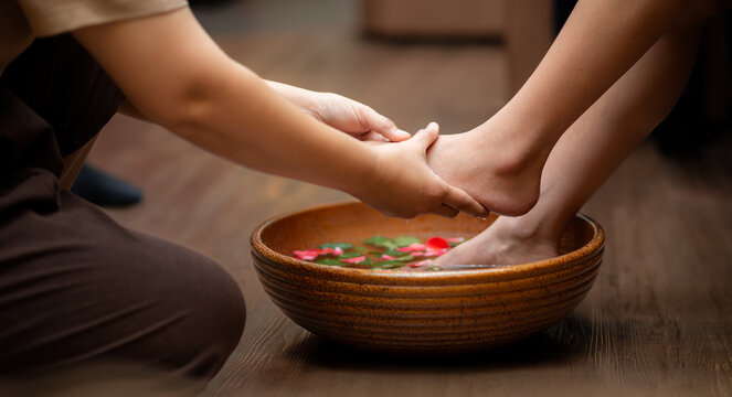 Woman soaks her feet in a bowl with flower petals