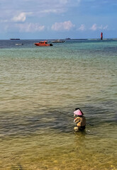 A fisherman is standing waist-deep in the sea and catching fish.