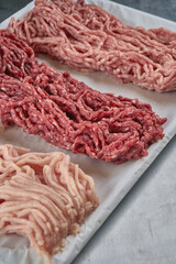 Assorted fresh minced meat from different types of meat in a butcher shop on a tray