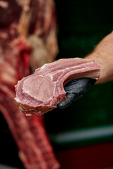 The butcher holds a piece of pork loin