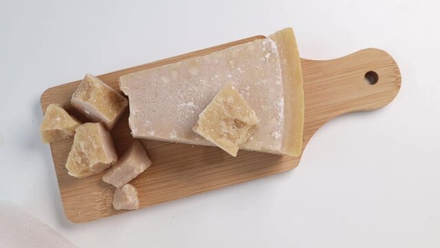Place a board with Parmesan cheese on the table. a piece of grana padano cheese