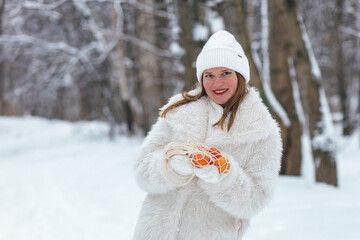 Orange tangerines lie in a cardboard eco-friendly chicken egg box. Women's hands on the street holding a box of tangerines in their hands