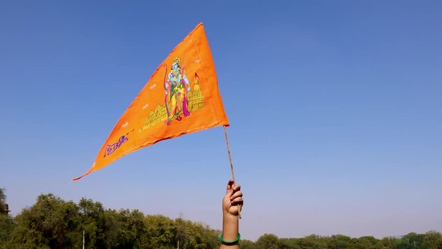 holy saffron flag with lord rama idol holing in hand with bright blue sky background at day