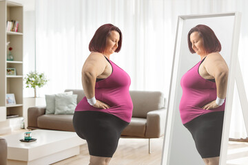 Fototapeta na wymiar Plus size woman in sportswear standing in front of a mirror