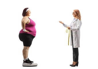 Doctor talking to a corpulent woman in sportswear on a weight scale