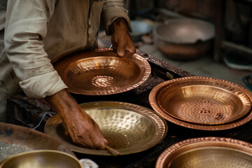 An Indian coppersmith, metalsmith, blacksmith, manufacturing hammered copper dishes for Indian restaurants.