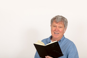 smiling happy mature man looking in camera, reading in a book and speaking