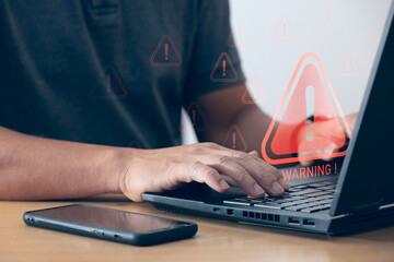 User uses laptop with warning triangle sign for error notification and maintenance concept Hacker...