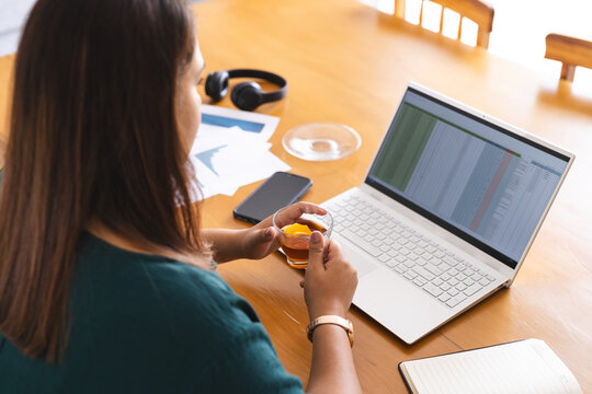 Young plus size biracial woman works at a home office setup - Powered by Adobe