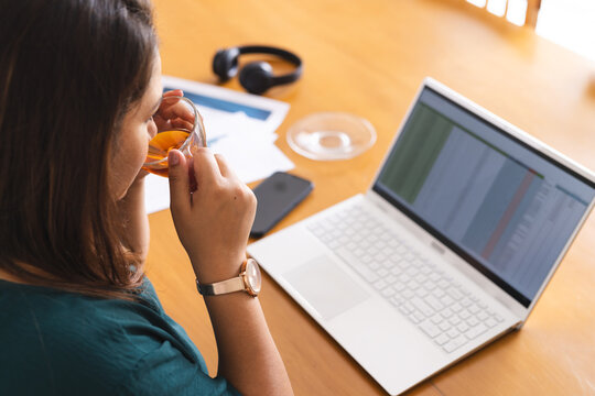 Young biracial plus size woman analyzes data on her laptop at home - Powered by Adobe