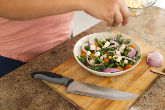 Person preparing a fresh salad at home, with copy space