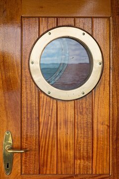 Closeup of round small porthole window on the side of vessel.