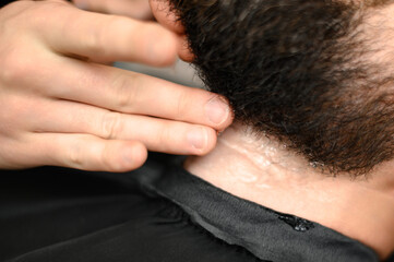 Fototapeta premium Barber applies shaving gel to the face of a bearded man