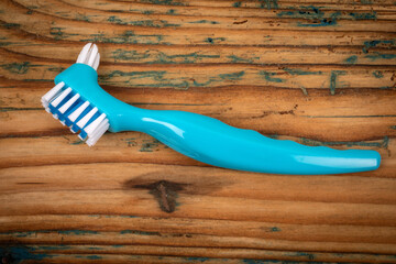 Denture toothbrush on a wooden background. Effective cleaning of teeth and gums