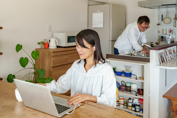 Obraz na płótnie Canvas パソコンで仕事をする女性と家事をする男性