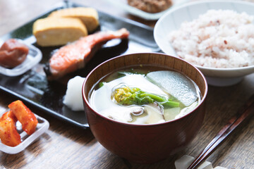 日本の家庭的な焼き鮭と卵焼きと雑穀米と菜の花と大根のお味噌汁と納豆とお漬物など