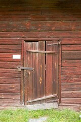 Old wood door on a weathered traditional painted red building.