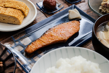 鮭の西京焼きと卵焼きと納豆と豆腐と油揚げとワカメのお味噌汁の梅干しなど家庭的な和朝食