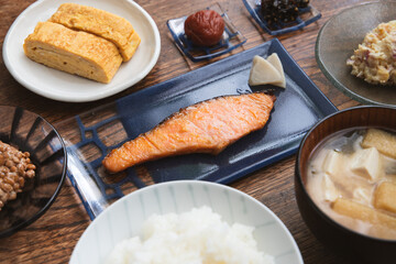 鮭の西京焼きと卵焼きと納豆と豆腐と油揚げとワカメのお味噌汁の梅干しなど家庭的な和朝食