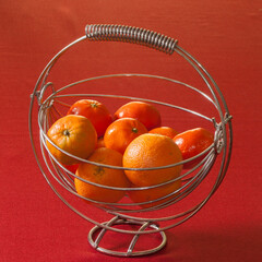 Oranges et mandarines dans un saladier en métal posé sur une nappe rouge