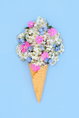 Surreal hawthorn blossom, forget me not and rose campion flower ice cream cone concept. Fun edible food art spring composition for logo, gift tag, birthday, mothers day, holiday vacation on blue.