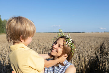 happy mom and son in a wheat field, the boy gently holds his mothers head. concept of parental love, motherhood. mothers Day. enjoy nature and life, family unity