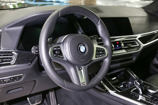 BMW X5 steering wheel and dashboard. Black leather interior of the SUV. The modern interior of a premium crossover. Car logo. 