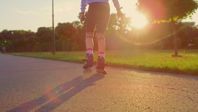 Back view of unrecognizable young woman rollerblading in the park