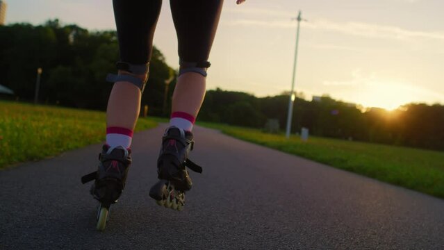 Back view of unrecognizable young woman rollerblading in the park