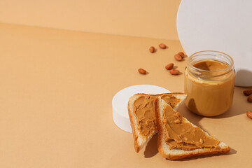 Peanut paste in a glass jar with toast, on a light background.