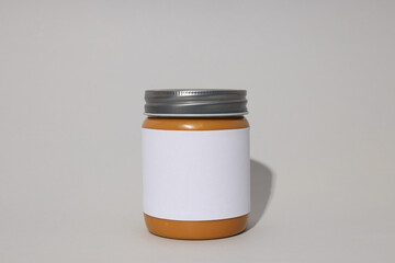 Peanut paste in a jar with a label, on a gray background.