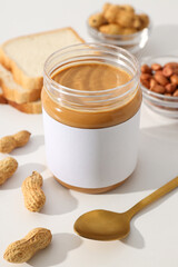 Peanut paste in a glass jar, on a light background.