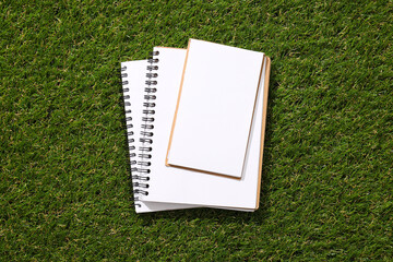 A paper notebook with a pencil on the grass.
