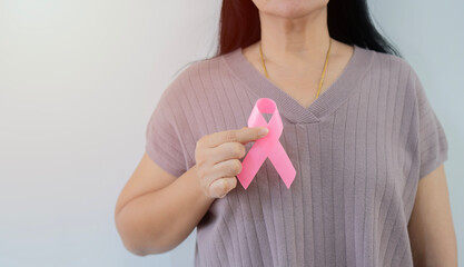 Woman with hand holding pink ribbon for supporting people living and illness. Healthcare