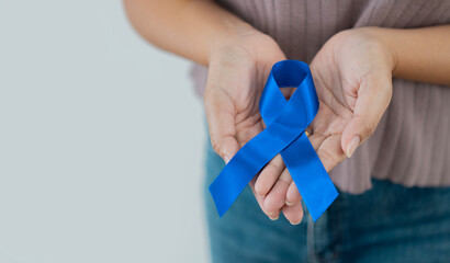 Cropped image of woman in casual wear with royal dark navy blue ribbon awareness in hand - Powered by Adobe