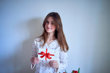 a gift certificate in the hands of a teenage girl wearing white pajamas with red hearts