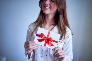 gift certificate in the hands of a teenage girl wearing white pajamas with red hearts