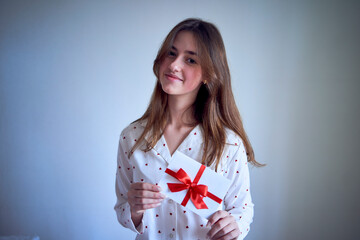 gift certificate in the hands of a teenage girl wearing white pajamas with red hearts