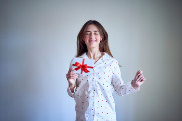 gift certificate in the hands of a teenage girl wearing white pajamas with red hearts