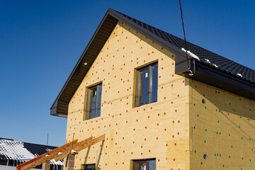 Fototapeta na wymiar Insulation of the building with mineral wool, the country house is sheathed with insulation, installation of thermal panels, construction of the house.