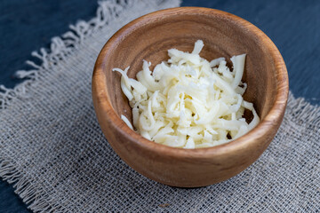 grated cheese for cooking in a wooden bowl in the kitchen