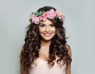 Happy woman with make-up, perfect white toothy smile and spring or summer season rose flower wreath on her long healthy shiny wavy hair, fashion beauty studio portrait