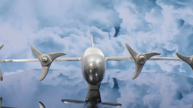 Macro lens view of silver model airplane with clouds in the background and video pulling back.