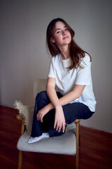 portrait of a beautiful teenage girl on a chair in a bright room in a minimalist style