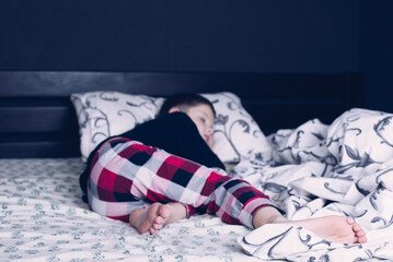Bare feet of a child. A child in pajamas. Bare feet sticking out from under the blankets. The boy...